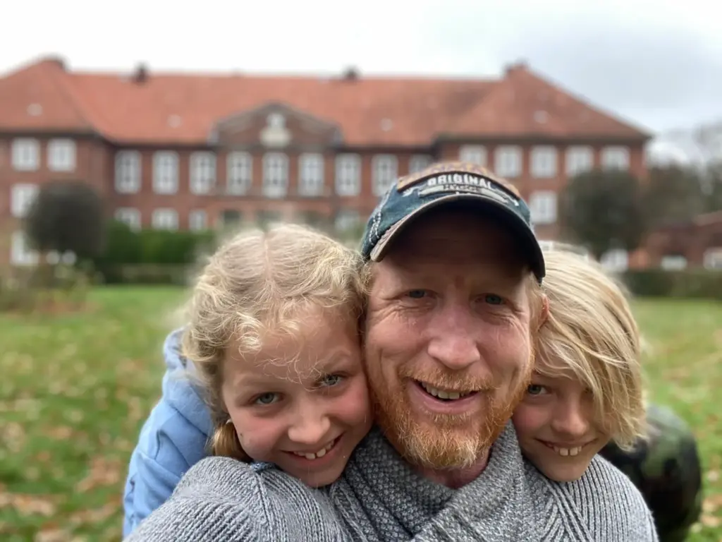 Jason with his two kids on a field in front of a large villa. Demonstrating that the people who work with him as a web designer are part of the family.