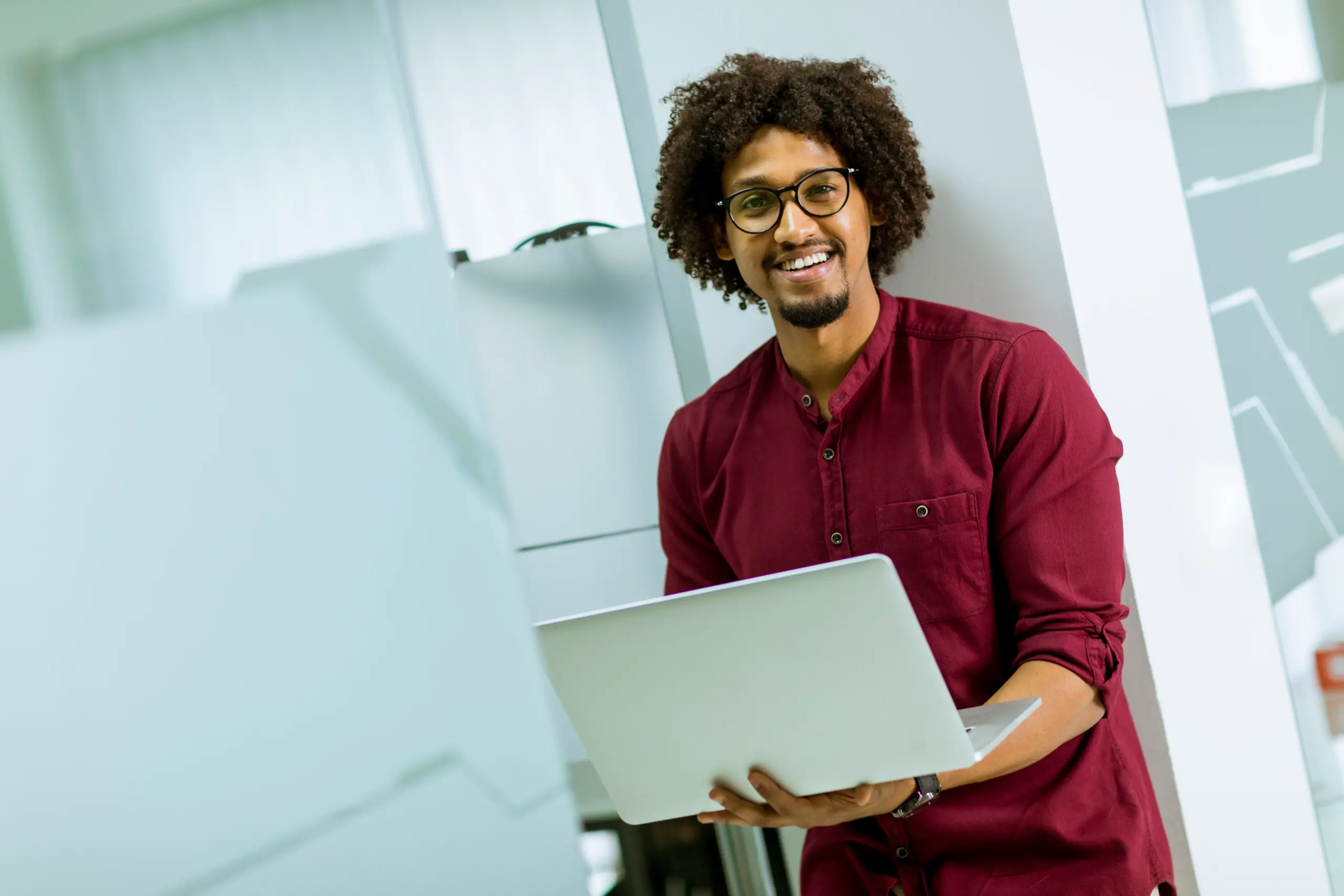 Man standing against wall with laptop and improving a company's conversion rate on their website.